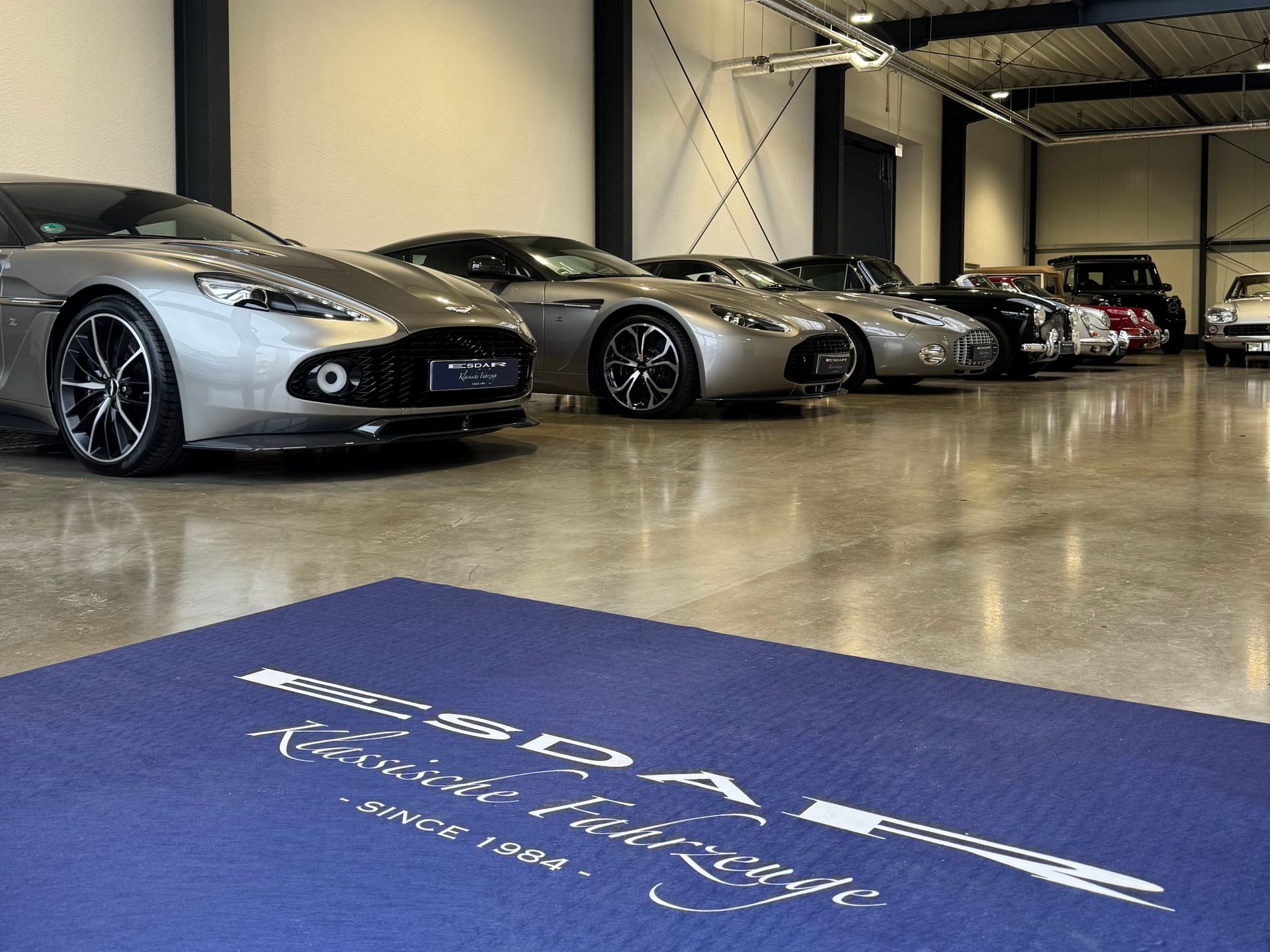 Aston-Martin-Lineup im Esdar-Showroom mit Logo am Boden